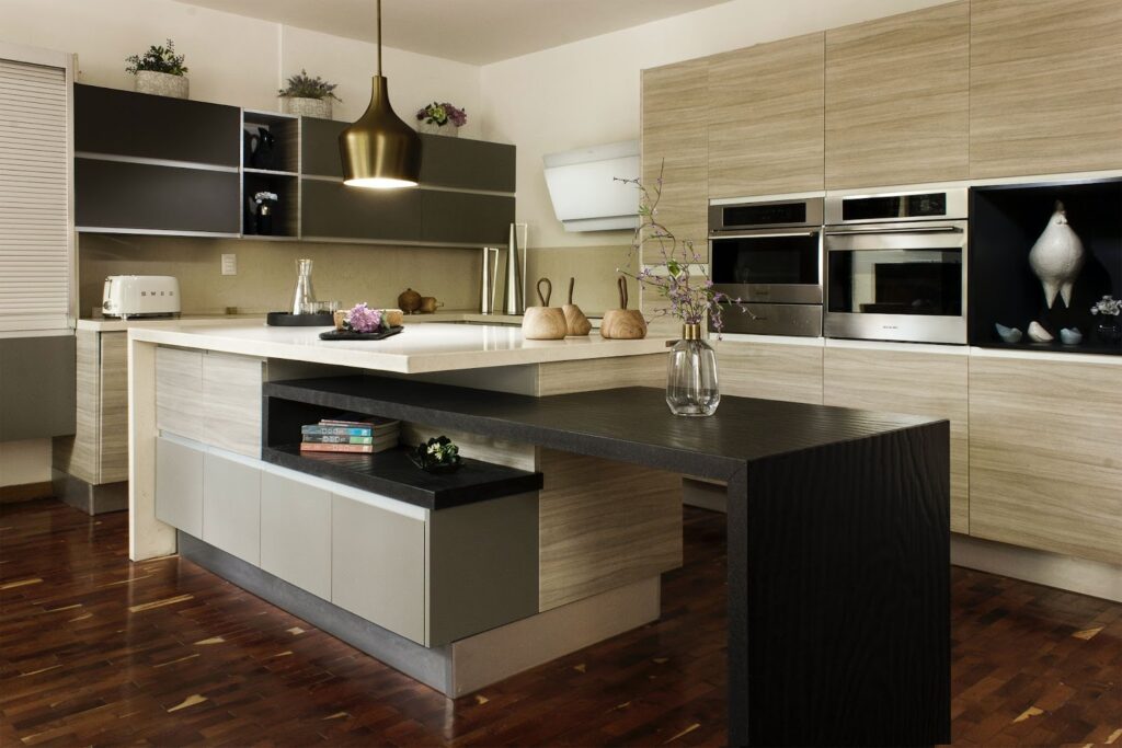 Modern kitchen with blonde wood cabinets, large island and brass hanging light fixture.